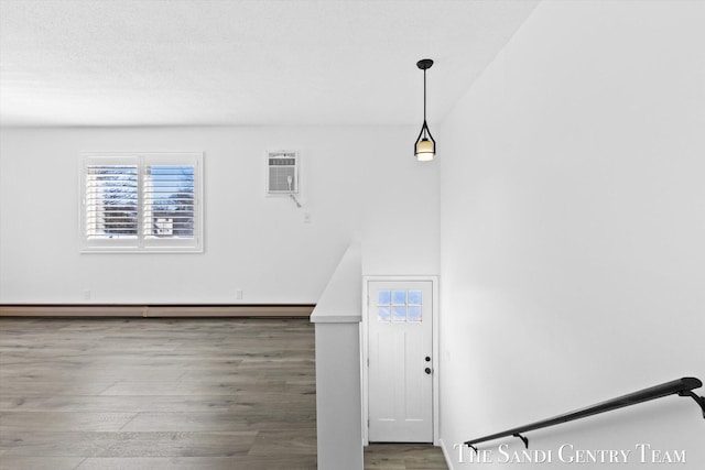 interior space featuring a baseboard radiator, wood-type flooring, and a wall mounted AC