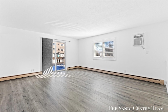 unfurnished room featuring hardwood / wood-style flooring, an AC wall unit, and a baseboard heating unit