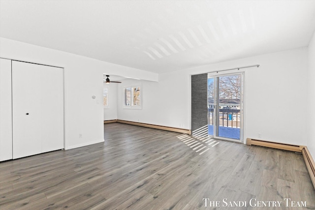 unfurnished living room featuring wood-type flooring, ceiling fan, and baseboard heating