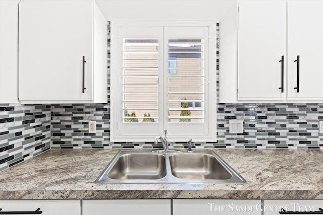 kitchen with white cabinetry, sink, and tasteful backsplash