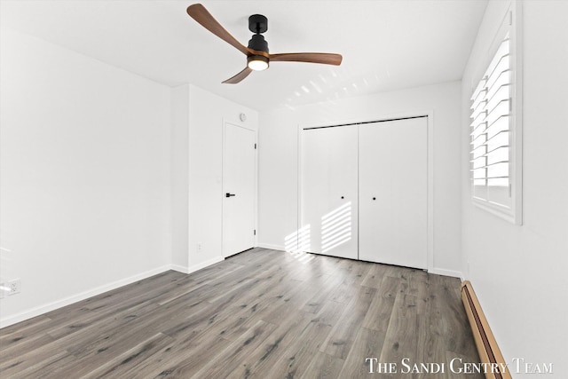 unfurnished bedroom with hardwood / wood-style flooring, a baseboard radiator, a closet, and ceiling fan