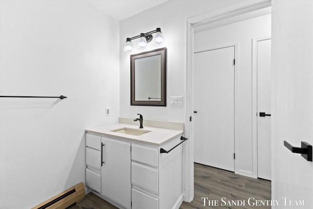 bathroom with vanity, hardwood / wood-style flooring, and baseboard heating