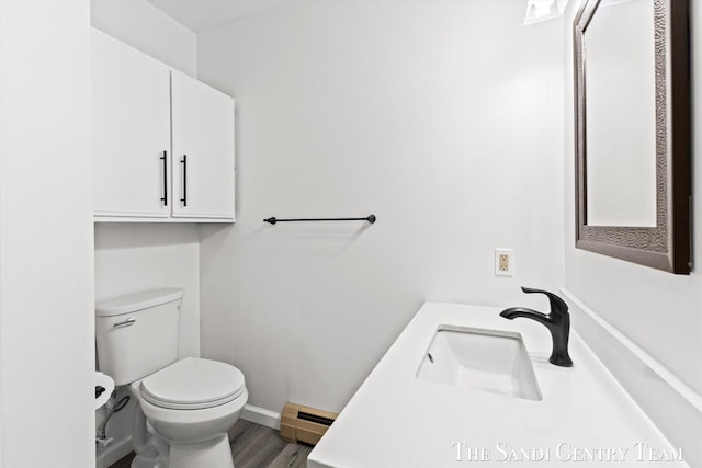 bathroom with wood-type flooring, vanity, baseboard heating, and toilet