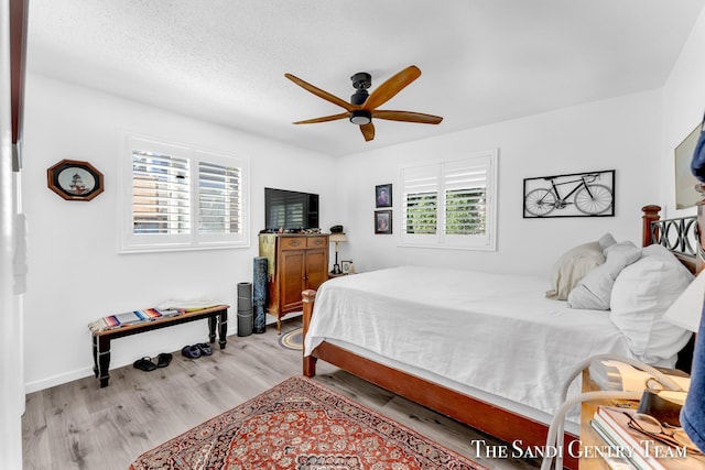 bedroom with ceiling fan, a textured ceiling, and light wood-type flooring