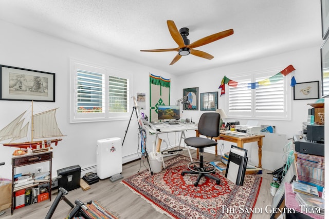 office space featuring baseboard heating, a textured ceiling, light hardwood / wood-style flooring, and a wealth of natural light