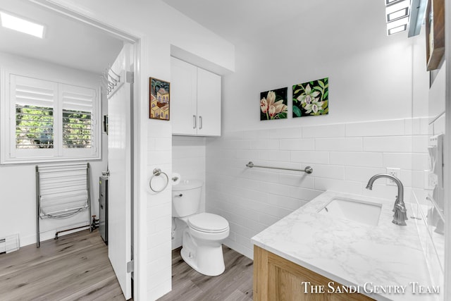 bathroom featuring hardwood / wood-style flooring, vanity, tile walls, and toilet