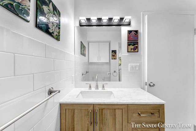 bathroom featuring vanity and tile walls