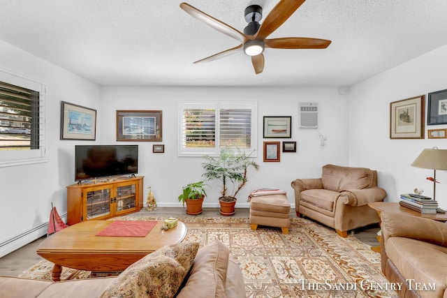 living room featuring a baseboard radiator, light wood-type flooring, a wall mounted AC, ceiling fan, and a textured ceiling