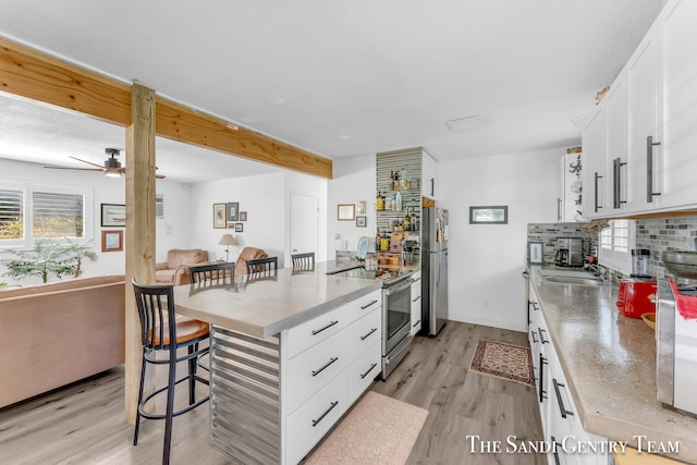 kitchen with white cabinetry, appliances with stainless steel finishes, a breakfast bar, and sink