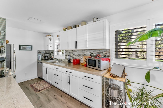 kitchen featuring tasteful backsplash, sink, white cabinets, and appliances with stainless steel finishes