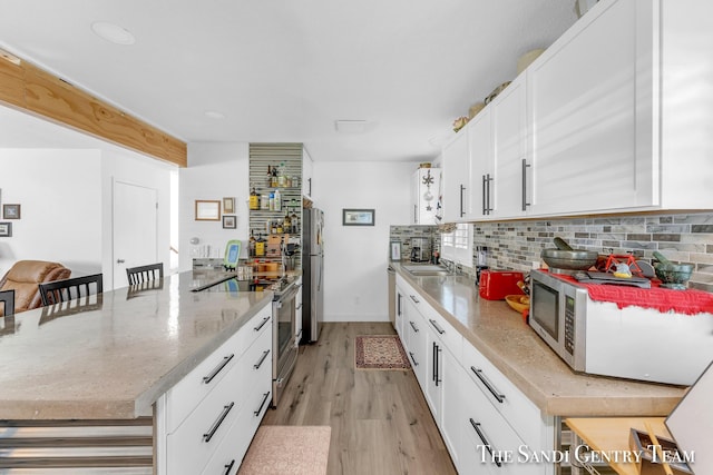 kitchen featuring appliances with stainless steel finishes, white cabinets, a kitchen bar, and decorative backsplash