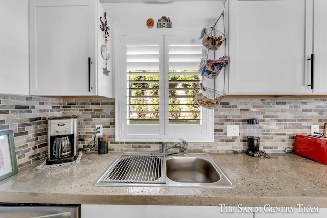 kitchen with sink, light stone counters, white cabinets, and backsplash