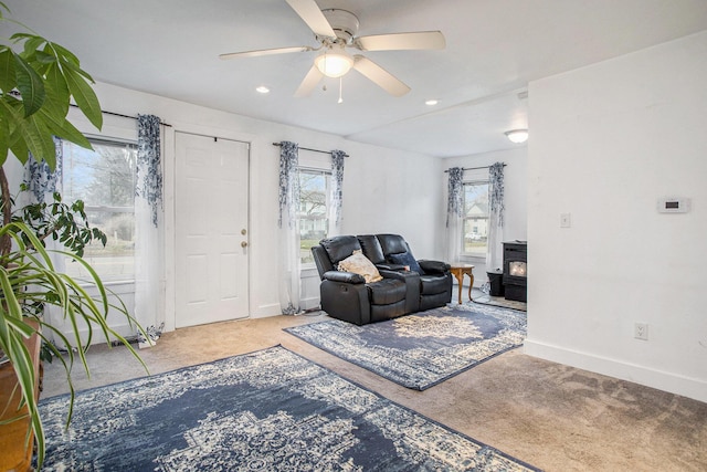 living room with carpet, a wood stove, and ceiling fan