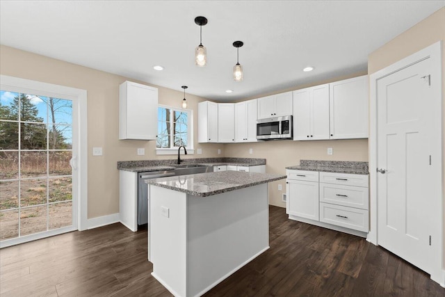 kitchen featuring white cabinetry, hanging light fixtures, a kitchen island, and appliances with stainless steel finishes