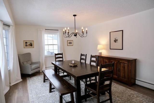 dining room featuring a baseboard heating unit, dark wood-type flooring, a notable chandelier, and a textured ceiling