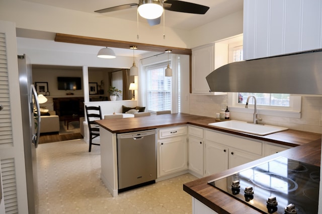 kitchen featuring butcher block countertops, sink, appliances with stainless steel finishes, white cabinetry, and hanging light fixtures