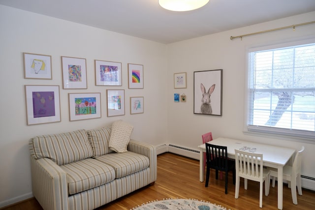 living area featuring a baseboard heating unit, light wood-type flooring, and a wealth of natural light