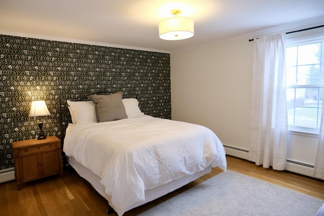 bedroom with hardwood / wood-style flooring, ornamental molding, and a baseboard radiator