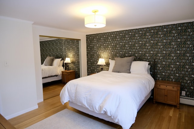 bedroom with hardwood / wood-style flooring, ornamental molding, and baseboard heating