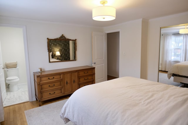 bedroom featuring crown molding, ensuite bath, and light wood-type flooring