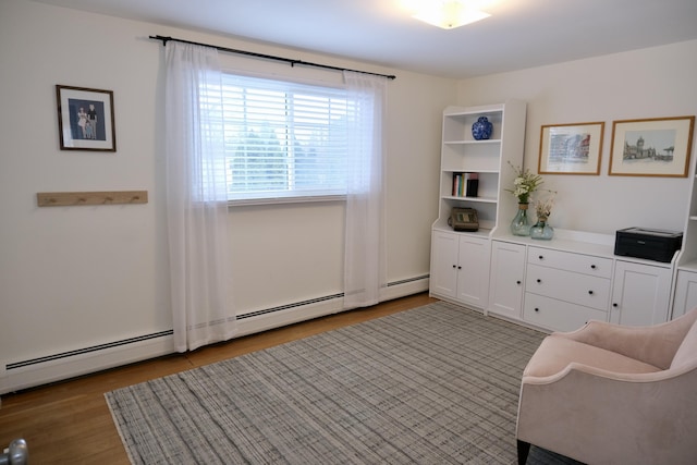 living area with hardwood / wood-style flooring and a baseboard heating unit