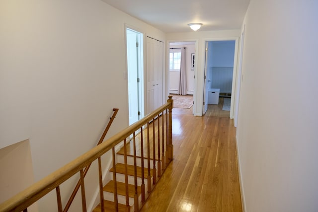 hall with baseboard heating and light hardwood / wood-style flooring