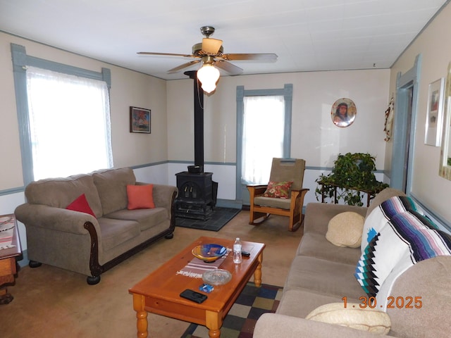 living room featuring light colored carpet, ceiling fan, and a wood stove