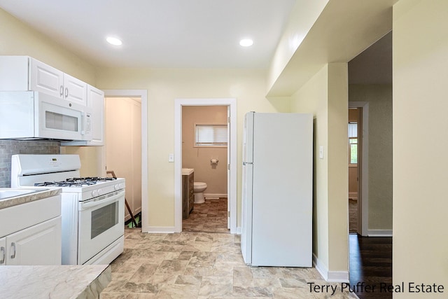 kitchen featuring backsplash, white cabinets, and white appliances