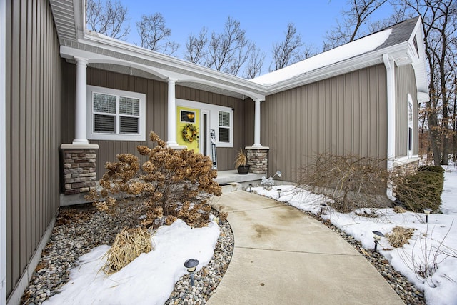 snow covered property entrance with covered porch