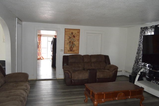 living area with arched walkways, dark wood finished floors, a textured ceiling, and baseboard heating