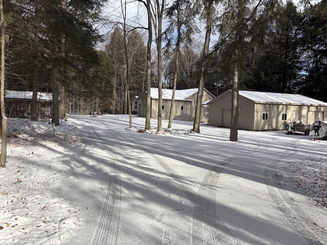 yard covered in snow featuring a garage and an outbuilding