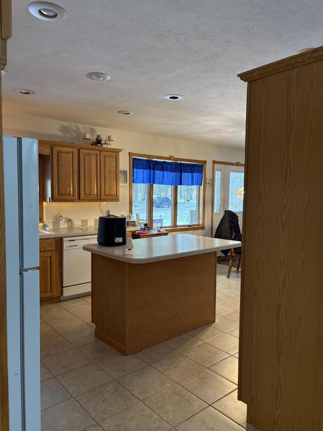 kitchen with white appliances, kitchen peninsula, a textured ceiling, and light tile patterned floors