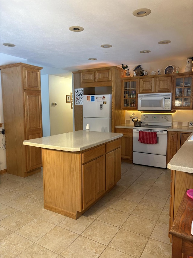 kitchen featuring sink, a center island, light tile patterned floors, and white appliances