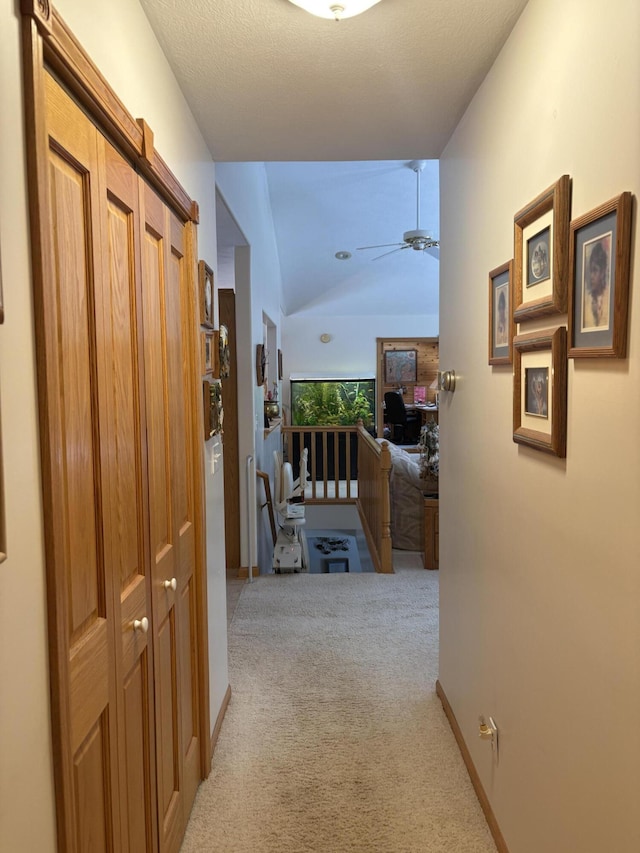 hall with light colored carpet and vaulted ceiling