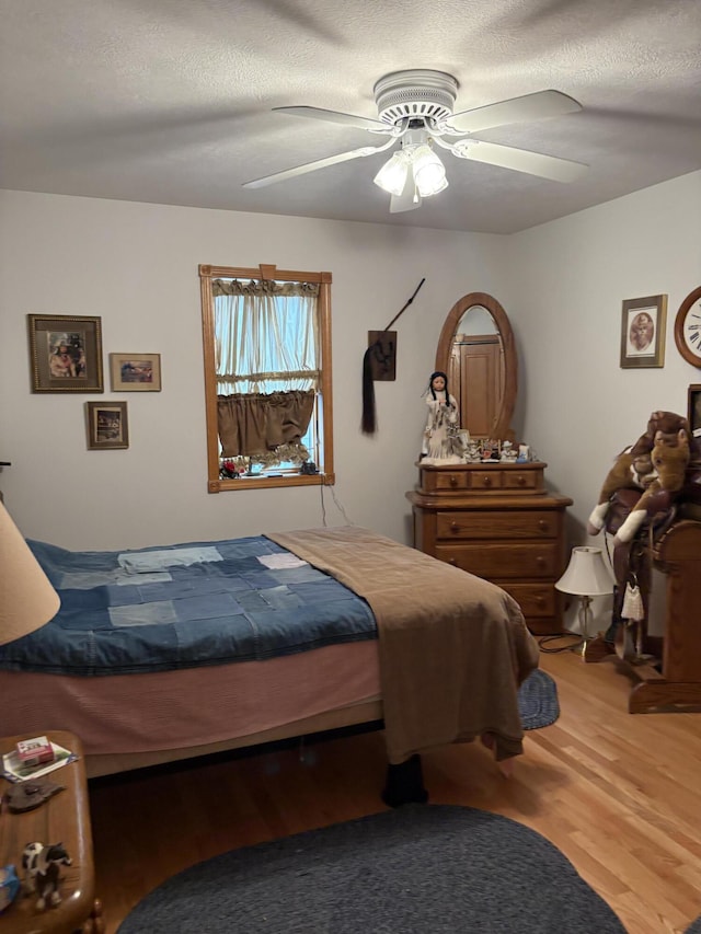 bedroom with hardwood / wood-style floors, a textured ceiling, and ceiling fan