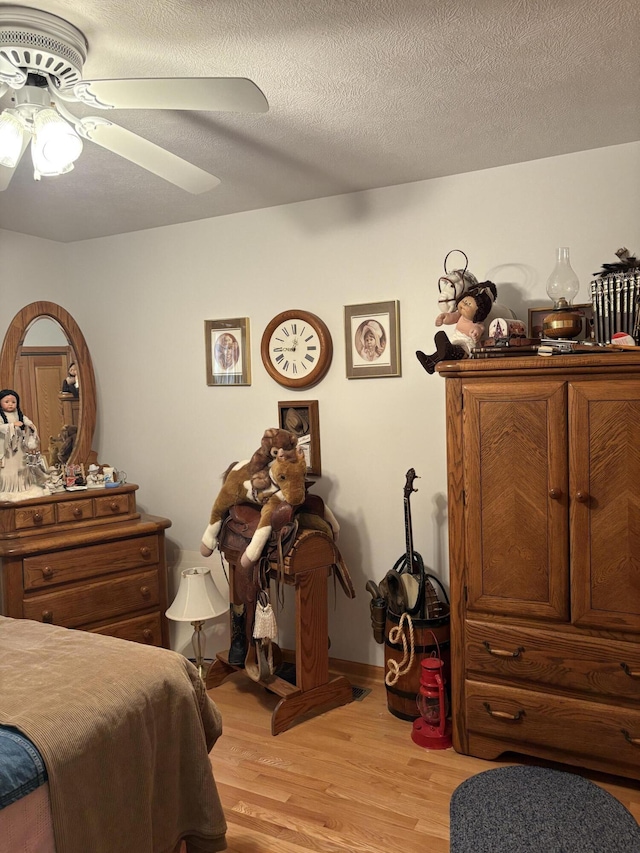 bedroom with ceiling fan, a textured ceiling, and light hardwood / wood-style floors