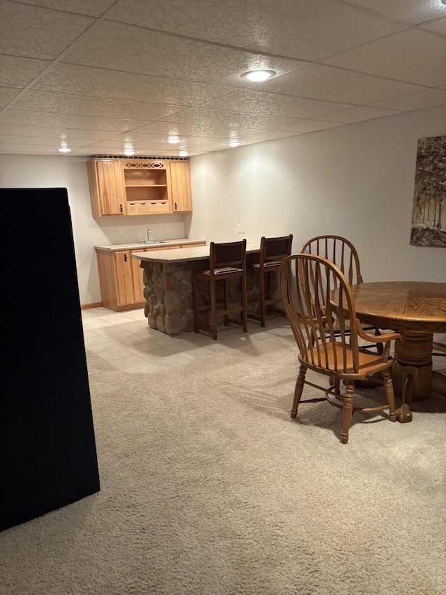 dining space with light carpet, wet bar, and a drop ceiling