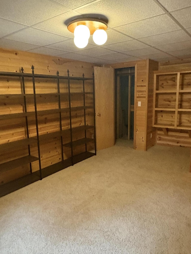 basement with a paneled ceiling and carpet