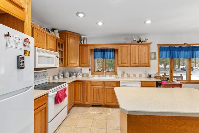 kitchen featuring white appliances, light tile patterned floors, sink, and a wealth of natural light