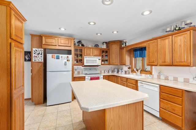 kitchen featuring white appliances, a center island, sink, and light tile patterned floors