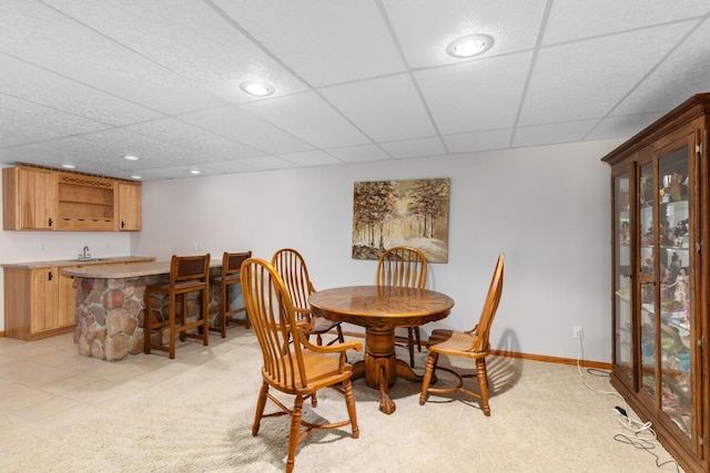 carpeted dining area featuring a paneled ceiling and wet bar