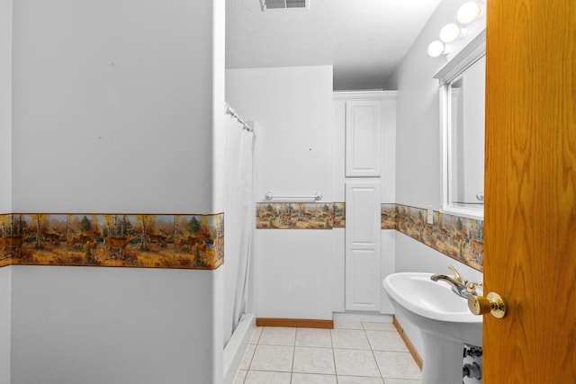 bathroom with tile patterned flooring, sink, and curtained shower