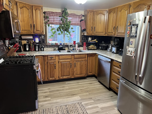 kitchen featuring stainless steel appliances, sink, decorative backsplash, and light wood-type flooring