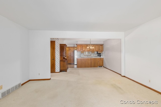 unfurnished living room featuring light carpet and a notable chandelier