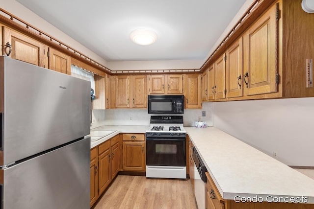 kitchen with stainless steel refrigerator, range with gas cooktop, dishwasher, sink, and light wood-type flooring