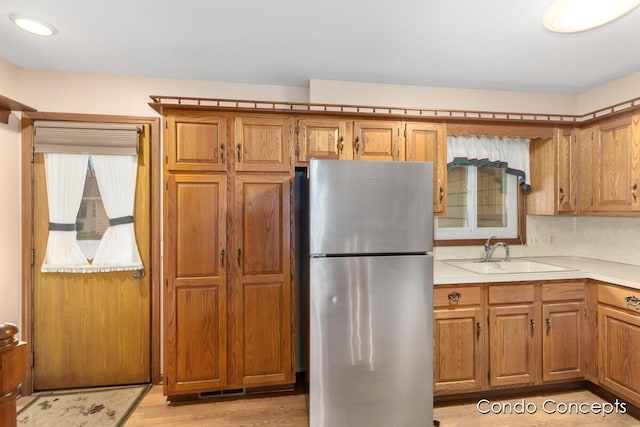 kitchen with sink, light hardwood / wood-style flooring, and stainless steel refrigerator