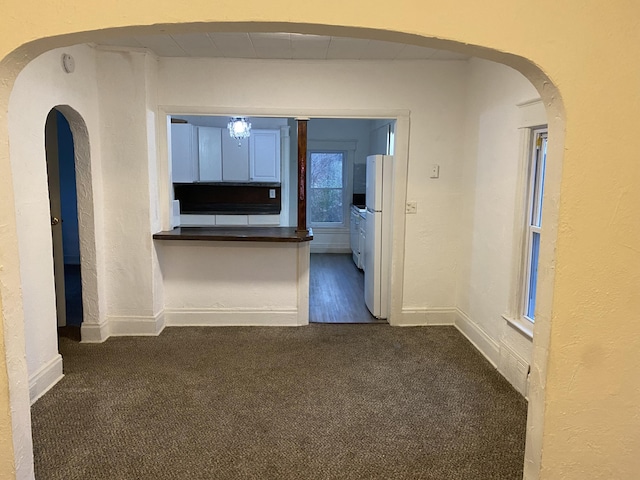 hall with dark colored carpet