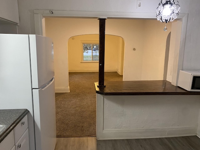 kitchen with white cabinetry, white appliances, and dark colored carpet