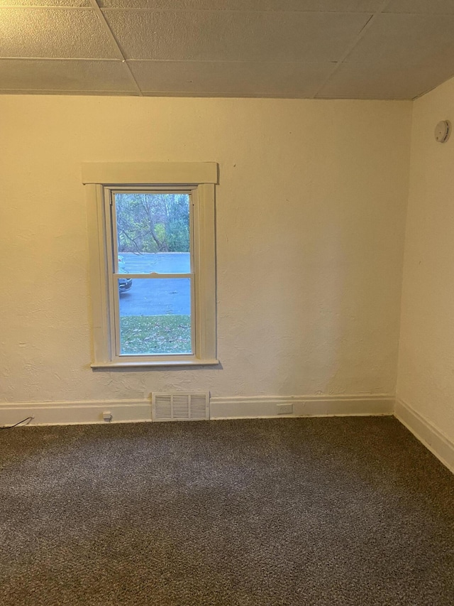 empty room with a drop ceiling and carpet floors