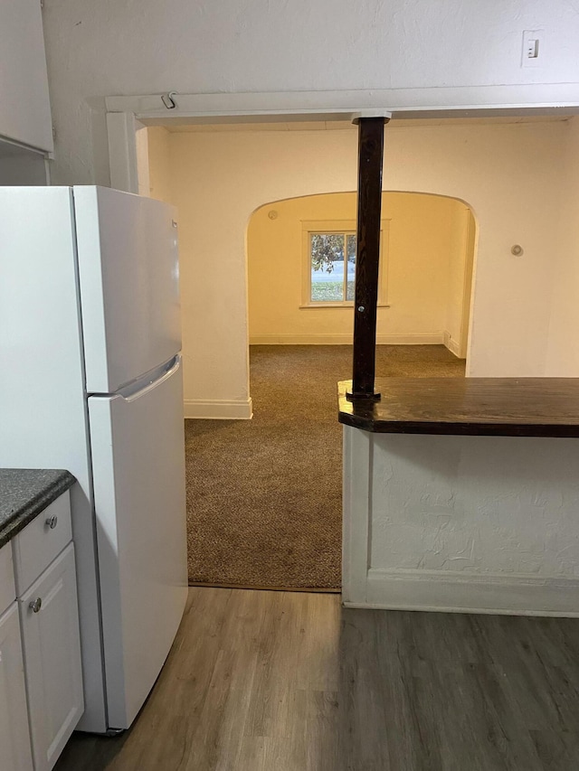 kitchen with white refrigerator, dark hardwood / wood-style floors, and white cabinets